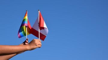 bandeira do canadá e bandeira do arco-íris, símbolo lgbt, segurando nas mãos, fundo azul, conceito para celebração lgbt canadá no mês do orgulho, junho, foco suave e seletivo, copie o espaço. foto