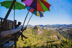 a garota sentada comendo macarrão na aldeia rural estilo pernas penduradas para o ponto de vista na montanha, as atrações locais da província de mae hong son na tailândia. foto