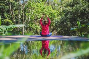 mulheres asiáticas relaxam no feriado. jogar se ioga na piscina. jovem viajar natureza ela exercício em pé. foto