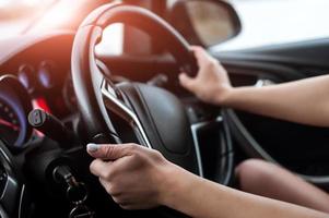 mãos femininas no volante, dentro do carro. foto