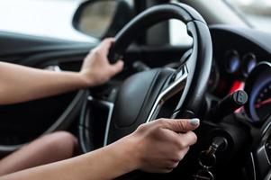 mãos femininas no volante, dentro do carro. foto