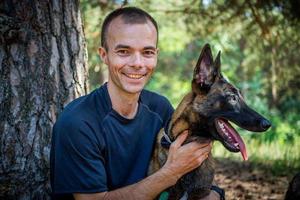 jovem hipster caucasiano passa tempo com seu cachorro no parque em um dia ensolarado de verão. o conceito de um animal de estimação como membro da família foto