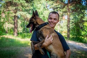 jovem hipster caucasiano passa tempo com seu cachorro no parque em um dia ensolarado de verão. o conceito de um animal de estimação como membro da família foto