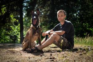 jovem hipster caucasiano passa tempo com seu cachorro no parque em um dia ensolarado de verão. o conceito de um animal de estimação como membro da família foto