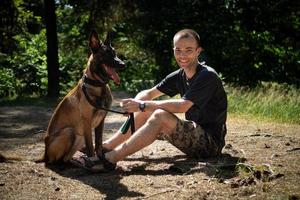 jovem hipster caucasiano passa tempo com seu cachorro no parque em um dia ensolarado de verão. o conceito de um animal de estimação como membro da família foto