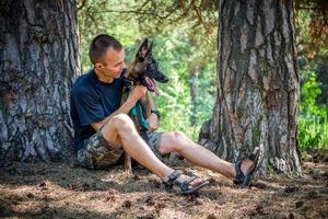 jovem hipster caucasiano passa tempo com seu cachorro no parque em um dia ensolarado de verão. o conceito de um animal de estimação como membro da família foto