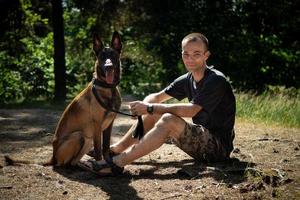 jovem hipster caucasiano passa tempo com seu cachorro no parque em um dia ensolarado de verão. o conceito de um animal de estimação como membro da família foto