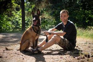 jovem hipster caucasiano passa tempo com seu cachorro no parque em um dia ensolarado de verão. o conceito de um animal de estimação como membro da família foto