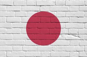 bandeira do japão retratada em cores de tinta na parede de tijolos antigos. banner texturizado em fundo de alvenaria de parede de tijolo grande foto