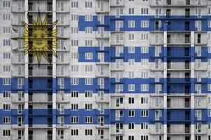 bandeira do uruguai retratada em cores de tinta em edifício residencial de vários andares em construção. banner texturizado no fundo da parede de tijolos foto