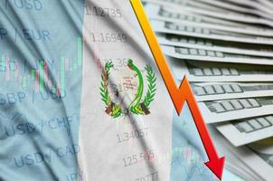 bandeira da guatemala e gráfico caindo posição do dólar americano com um leque de notas de dólar foto