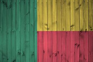 bandeira do benin retratada em cores brilhantes de tinta na parede de madeira velha. banner texturizado em fundo áspero foto