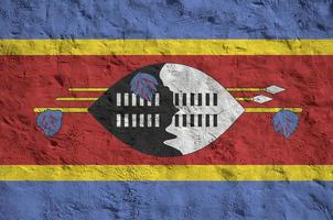bandeira da suazilândia retratada em cores de tinta brilhante na parede de reboco em relevo antigo. banner texturizado em fundo áspero foto