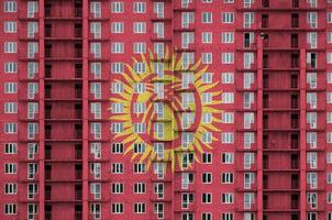 bandeira do quirguistão retratada em cores de tinta em prédio residencial de vários andares em construção. banner texturizado no fundo da parede de tijolos foto