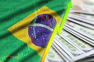 bandeira do brasil e gráfico aumentando a posição do dólar americano com um leque de notas de dólar foto