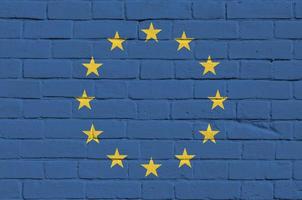 bandeira da união europeia retratada em cores de tinta na parede de tijolos antigos. banner texturizado em fundo de alvenaria de parede de tijolo grande foto