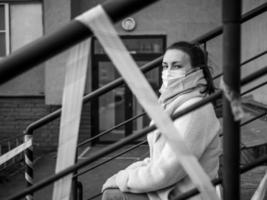foto de uma menina com uma máscara. sentado na rua com fitas de aviso de perigo.