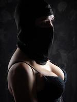 retrato de uma menina em uma balaclava preta e um sutiã preto. foto