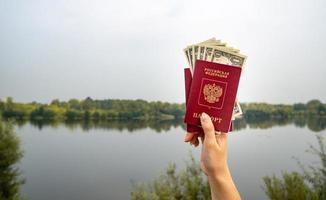 passaporte estrangeiro e dólares na mão, no contexto da natureza. foto