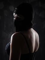 retrato de uma menina em uma balaclava preta e um sutiã preto. foto