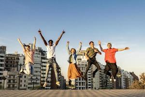 felizes amigos da geração do milênio pulando ao ar livre foto