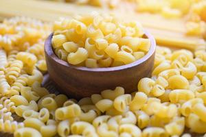 macarrão cru na tigela de madeira, macarrão vários tipos de macarrão cru espaguete e macarrão no fundo, conceito culinário de comida italiana, coleção de diferentes massas cruas para cozinhar alimentos foto