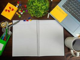 configuração plana, maquete de papel. espaço de trabalho no fundo da mesa de escritório da vista superior. com papel branco em branco, laptops, material de escritório, lápis, folhas verdes e xícaras de café em uma mesa de madeira. foto