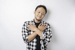 retrato de um pacífico homem asiático vestindo camisa xadrez está sorrindo e sentindo alívio foto