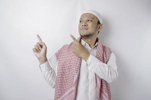 homem muçulmano asiático animado apontando para o espaço da cópia ao lado dele, isolado pelo fundo branco foto