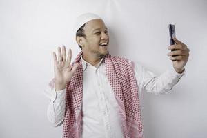 um retrato de um homem muçulmano asiático feliz sorrindo enquanto segura seu telefone, isolado pelo fundo branco foto