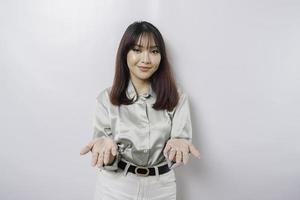 jovem mulher asiática vestindo camisa verde sálvia apresentando uma ideia enquanto olha sorrindo no fundo branco isolado foto