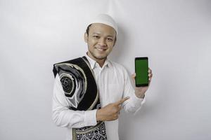 um retrato de um homem muçulmano asiático feliz sorrindo enquanto mostra o espaço da cópia em seu telefone, isolado pelo fundo branco foto