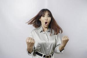 uma jovem mulher asiática com uma expressão de sucesso feliz vestindo camisa verde sálvia isolada por fundo branco foto