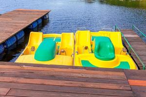 pedalinhos ou pedalinhos estação de catamarãs. bicicletas de água amarela trancadas no cais de doca do lago marina em dia ensolarado de verão. atividade de lazer de verão ao ar livre. foto