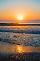 belo pôr do sol de verão na praia, ondas e areia foto