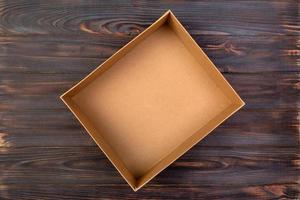 caixa de papelão aberta sobre uma mesa escura, fundo de madeira. vista do topo foto