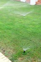 aspersor no jardim molhando o gramado. conceito de gramados de rega automática foto