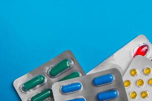 pílulas coloridas, comprimidos e cápsulas em um fundo azul. medicina e saúde. foto