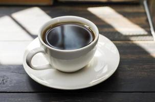 xícara de café branco com café preto ou chá. colocar na mesa ou mesa de leitura - vista superior foto