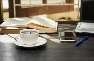 uma xícara de café branca é colocada sobre a mesa. escritório ou em casa com um notebook teclado de computador tablet pc foto