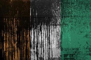 bandeira da costa do marfim retratada em cores de tinta na parede de barril de óleo velho e sujo. banner texturizado em fundo áspero foto