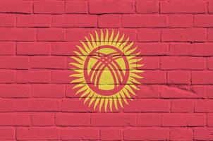 bandeira do quirguistão retratada em cores de tinta na parede de tijolos antigos. banner texturizado em fundo de alvenaria de parede de tijolo grande foto