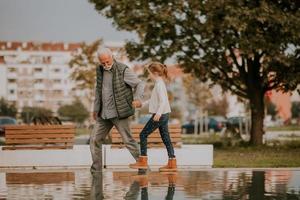 avô passar tempo com sua neta por pequena piscina de água no parque em dia de outono foto