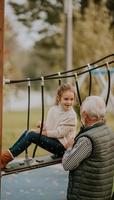 avô passar tempo com sua neta no parque infantil no dia de outono foto