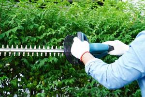 jardineiro aparando mato por tesouras de poda elétricas no jardim. passatempo em casa. foto