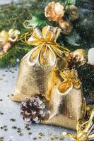 sacos de ouro com presentes de natal no fundo das árvores de natal e fundo cinza de decorações. conceito de saudações de ano novo. foto