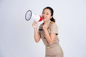 jovem mulher asiática em roupas de trabalho de uniforme marrom segurando o megafone isolado no fundo branco, fala e anuncia o conceito