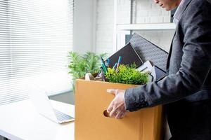 o trabalhador desempregado está colocando coisas em uma caixa de papelão marrom para mudar para um novo emprego. foto