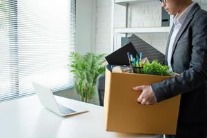 jovens empresários usam ternos cinza, sentem-se estressados e embalam itens em caixas de papelão. conceitos de desemprego e negócios foto