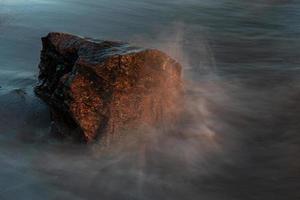 pedras na costa do mar báltico ao pôr do sol foto